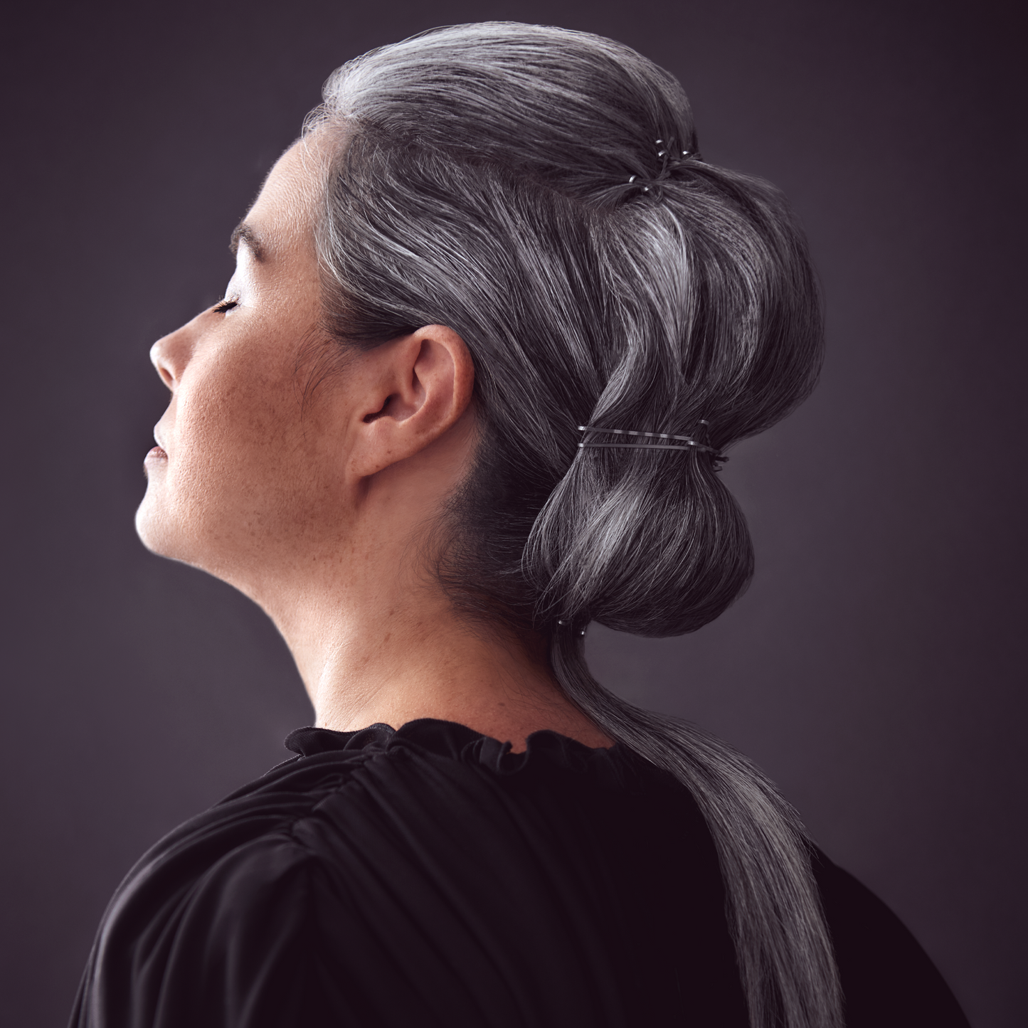 A portrait of a silver-haired woman, eyes closed and calm with a hairstyle that is unique and controlled. Hair tone is yellow-free.